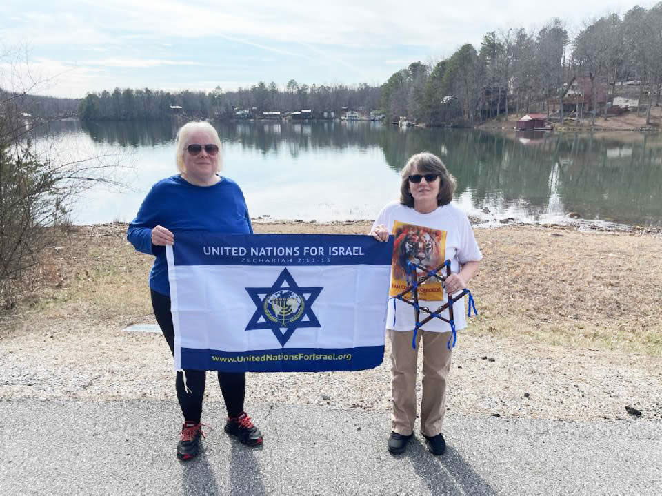 Two women with UNIFY flag by the lake