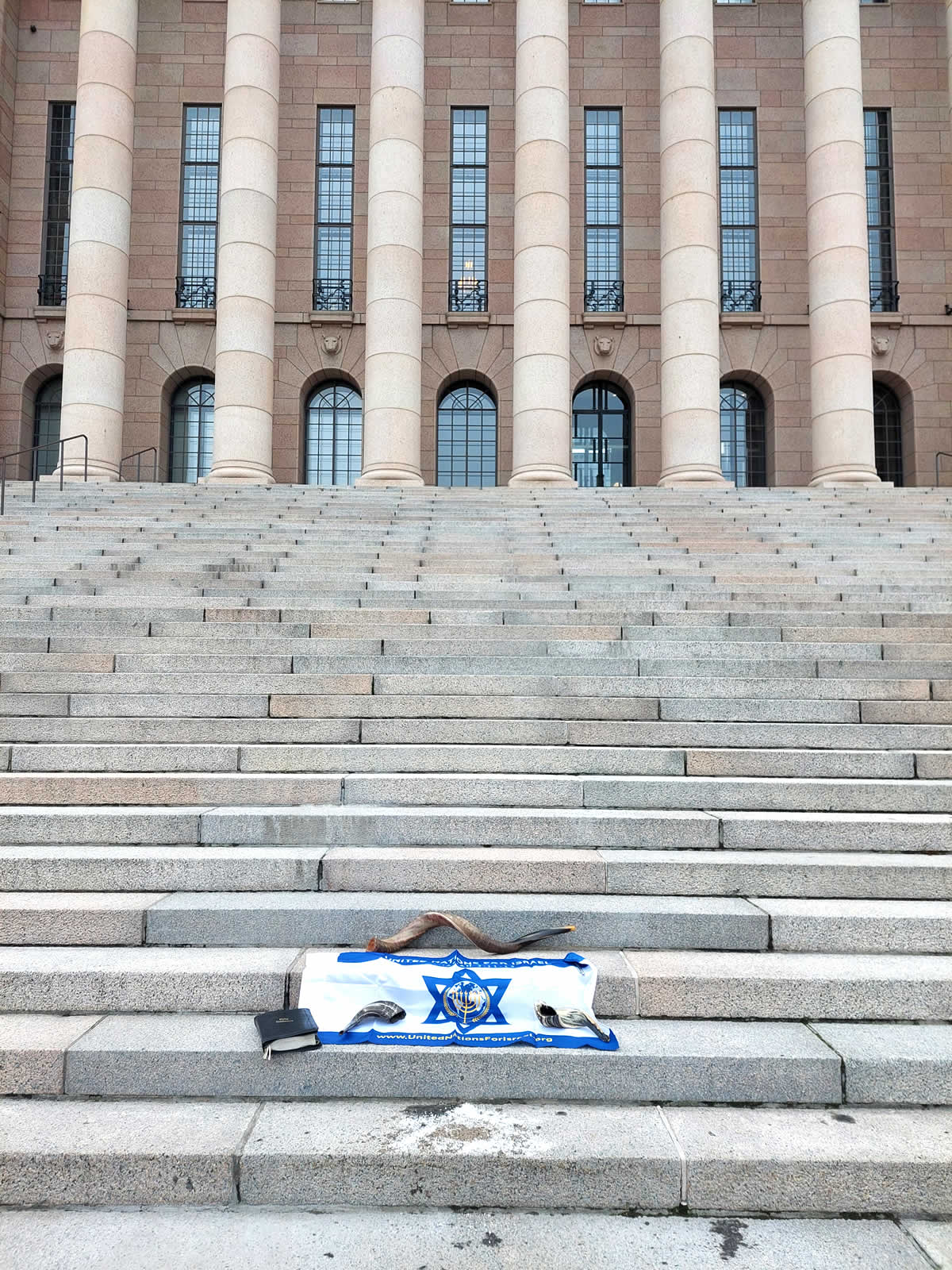 UNIFY flag, shofar and Bible on stairs in front of a large building