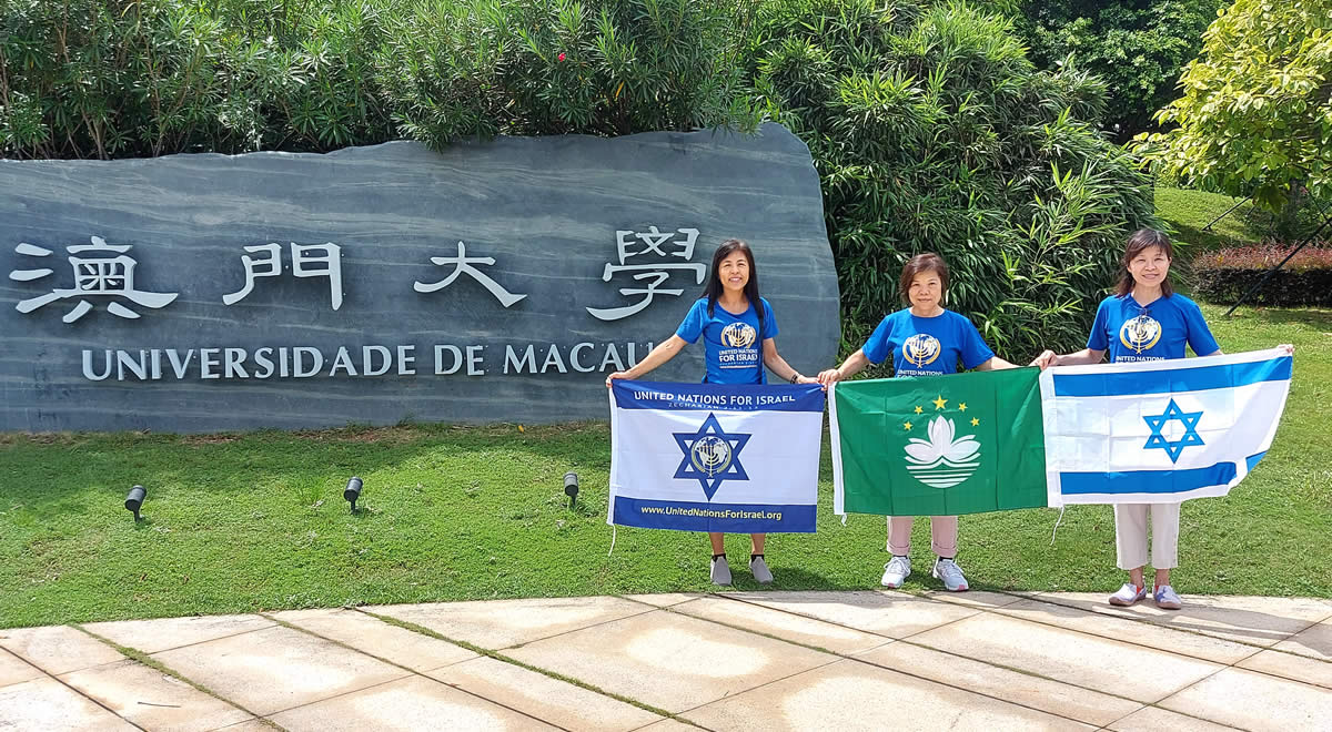 Three women holding UNIFY and Israel flags in Macau