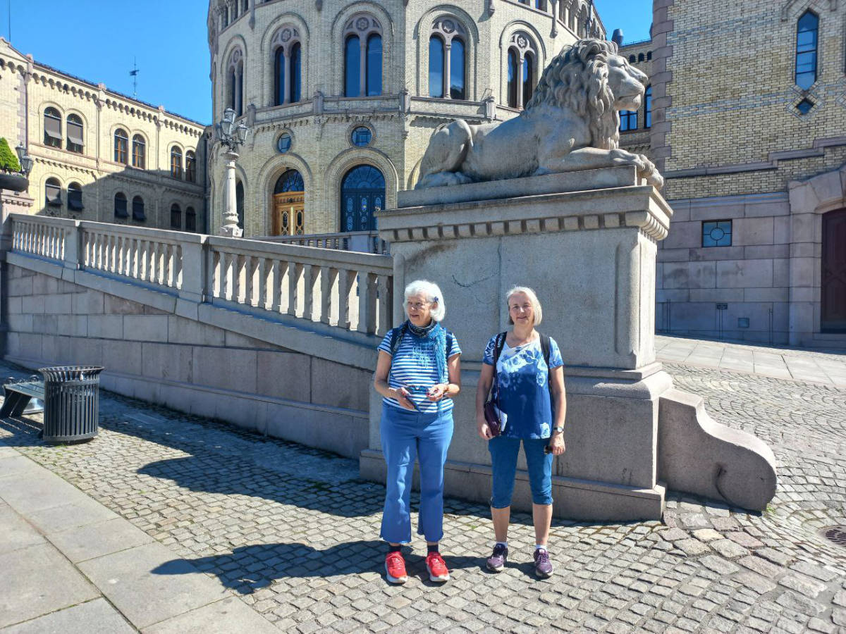 Two elderly women in front of a lion statue