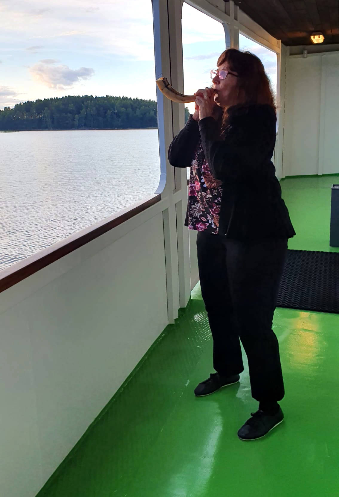 Woman blowing shofar on a lake boat