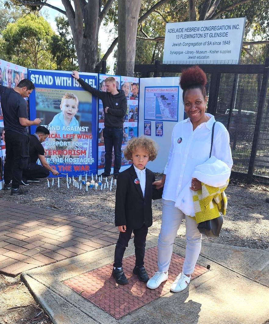 Black woman with a little boy in front of Stand with Israel posters