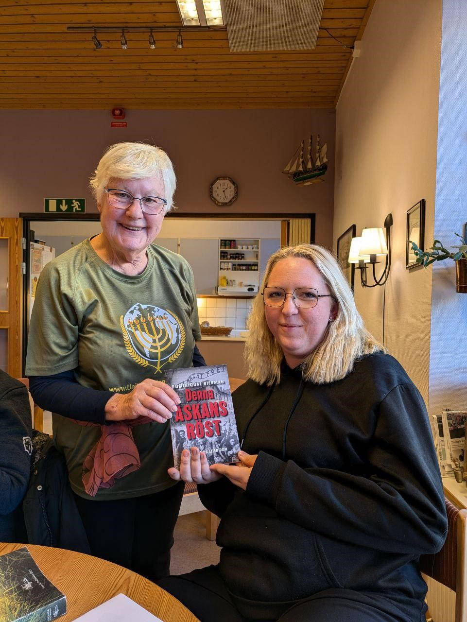 Two women holding The Voice of These Ashes book